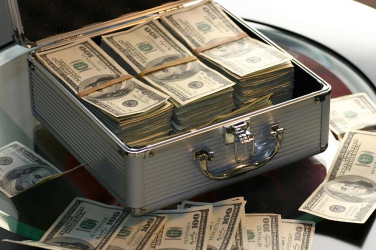 Free Open briefcase filled with stacks of hundred dollar bills on a glass table, representing wealth. Stock Photo