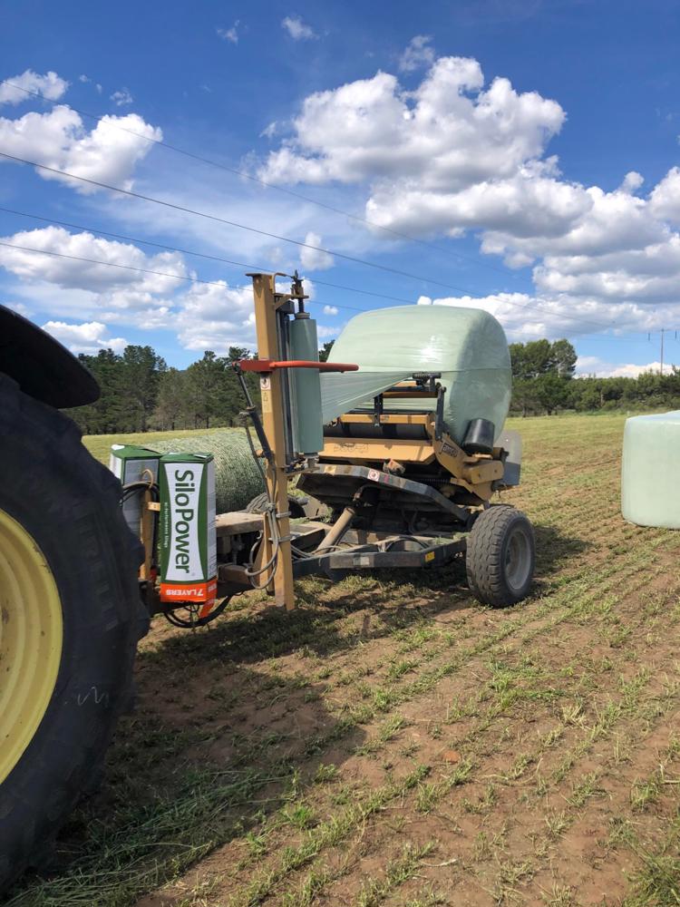 Baling machine applying high-quality silage wrap to bales in the field, showcasing durable bale wrap from Baling Twine. Baling machine applying high-quality silage wrap to bales in the field, showcasing durable bale wrap from Baling Twine.