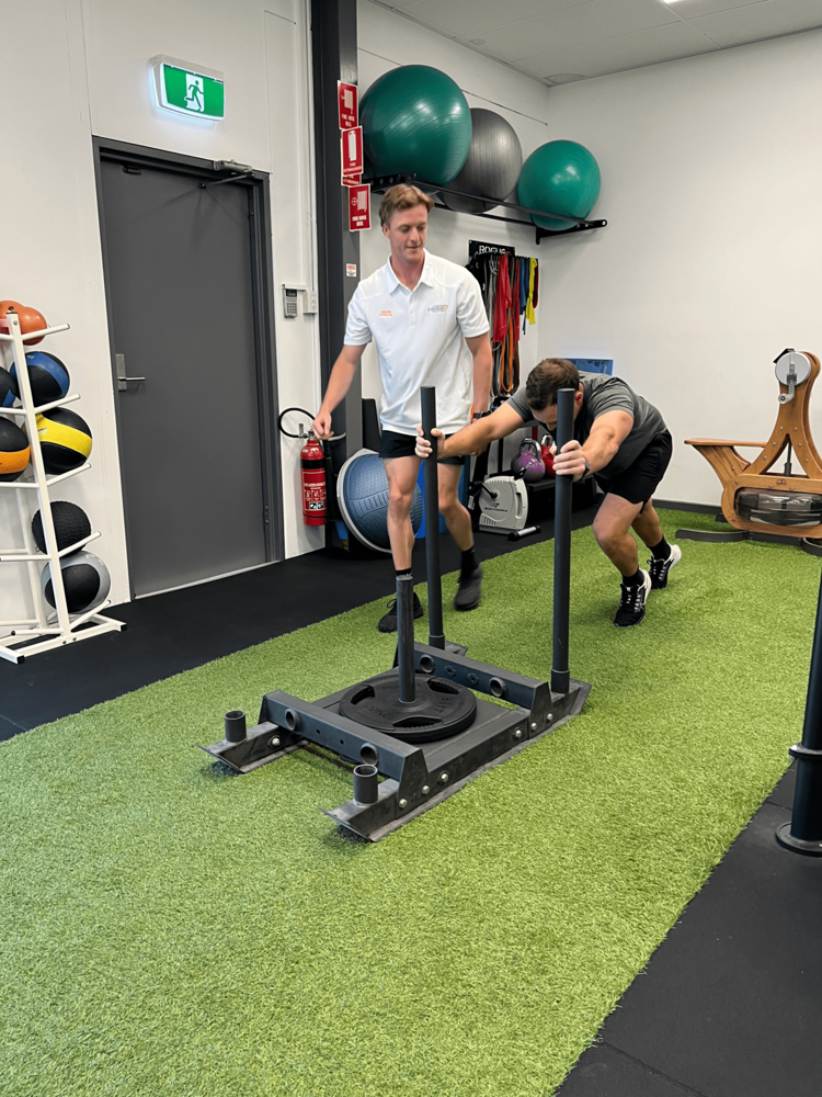 Exercise Physiology Adelaide session at Inertia Health Group with an exercise physiologist supervising sled push strength training for rehabilitation services, cardiovascular health and musculoskeletal treatment. Exercise Physiology Adelaide session at Inertia Health Group with an exercise physiologist supervising sled push strength training for rehabilitation services, cardiovascular health and musculoskeletal treatment.